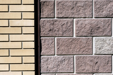 Wall with facing bricks. Different types of bricks on the facade of the fence. Yellow and gray bricks. Stone wall background.