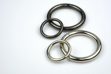 Metallic black and gray chrome rings for making bags and backpacks. High quality sewing accessories. Large and small metal rings on a white background.
