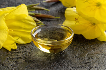 A bowl of evening primrose oil with blooming evening primrose plant
