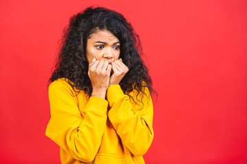 Surprised shocked amazed beautiful curly black african american woman isolated over red background.