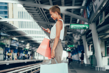 Smiling woman using phone at train station 