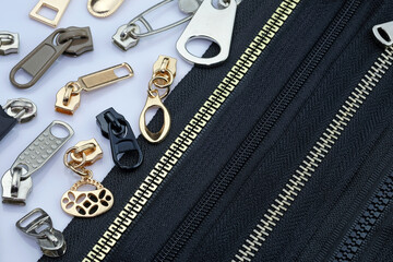 Zipper on a black fabric base with different color runners. different types of metal zipper slider...