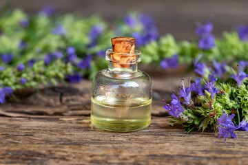 Obraz na płótnie Canvas A bottle of essential oil with fresh blooming hyssop twigs
