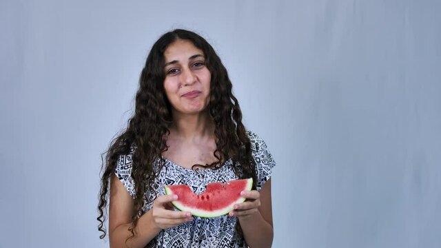 Happy teenage girl with long curly hair eating watermelon, white background
