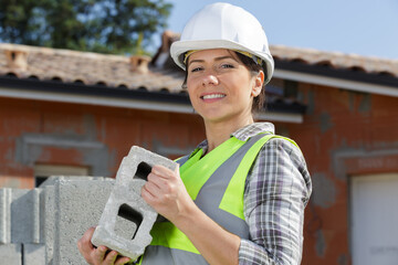 woman builder holding a brick wall