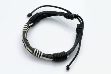 Fototapeta premium Black and white leather bracelet on a hand on a white background. Leather accessories, arm bracelet. Wrist bracelet made of leather and thread.