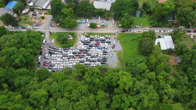 AERIAL: Revealing Drone Shot of a Parking Zone full by Cars surrounded by Jungle forest, stuck in the Queue waiting for the Ferry from Koh Chang Island to Mainland, Trat, Thailand, Asia. Bird Eye View