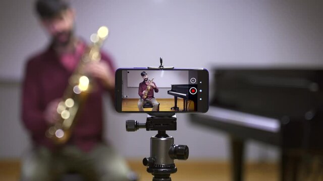  Online Music Class. Saxophone teacher recording course with smartphone in times of Coronavirus. Online learning and education