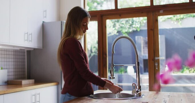 Woman washing her hands in the sink at home