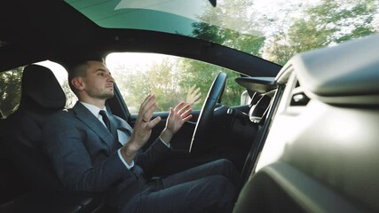 Confident business man driving an autonomous car. Vehicle starts autonomous self-driving. Hands free system. Concept of Driverless Future Technology in transport - Powered by Adobe