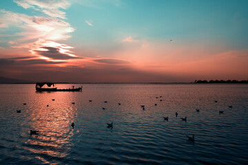 Silhouette of a fishing boat and seagulls on the sea on sunset.
