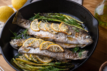 grilled trout with lemon and herb on iron skillet pan