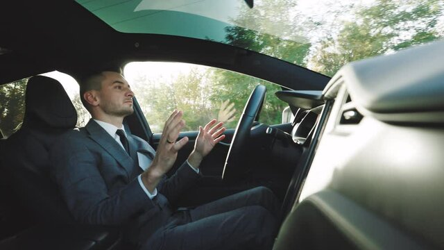 Confident business man driving an autonomous car. Vehicle starts autonomous self-driving. Hands free system. Concept of Driverless Future Technology in transport