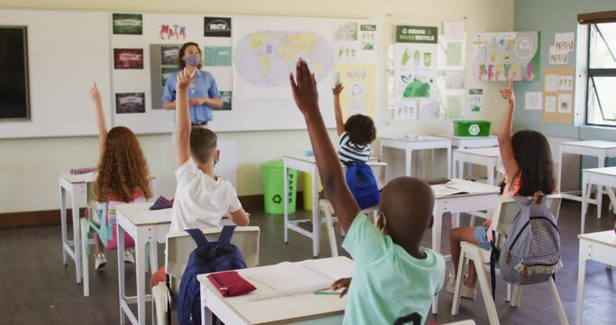Group of kids raising their hands in the class at school