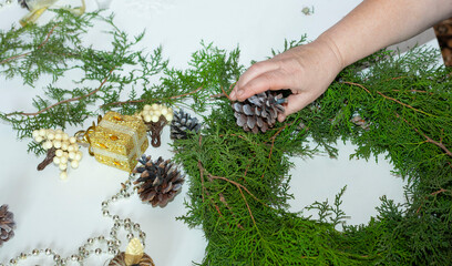 Female hands make a Christmas wreath. New Year's decorations. Christmas decorations.