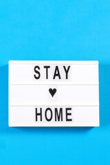 White lightbox with text STAY HOME on light blue background. Top view