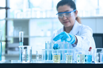 Scientist woman working with liquids in glassware. Asian scientist works in modern biological lab....