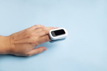 Man using modern fingertip pulse oximeter on light background, close up