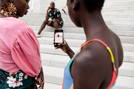 Young Woman With Camera Phone Photographing Stylish Man On Steps