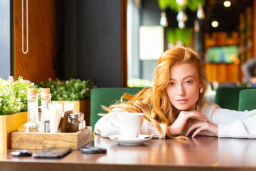 Obraz na płótnie Canvas Woman at a cafe drinks tea or coffee.