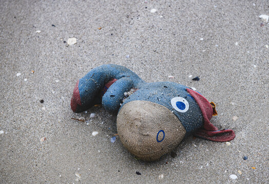 Discard garbage old fabric doll on the beach.
