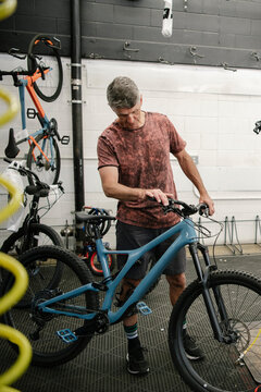 Male bike shop mechanic fixing mountain bike in workshop