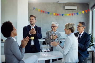 Happy business people opening bottle of Champagne while celebrating at office party.