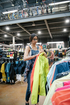 Female bike shop owner arranging clothing merchandise