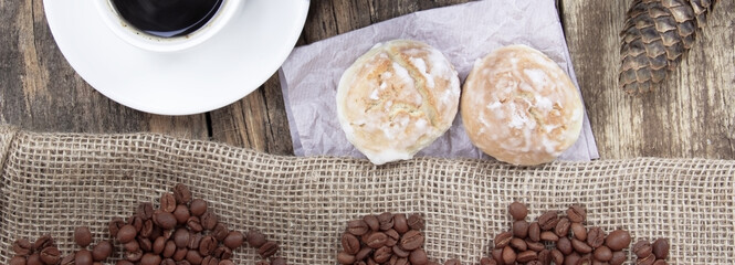 A white cup of coffee and cake on a wooden background. Banner.Coffee beens on a linen fabric. Cone