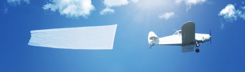 Fototapeta na wymiar Flying airplane aircraft with string pulling and a white copy space banner