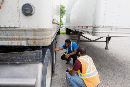 Trucker and warehouse worker checking tire of container semi truck