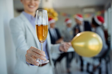 Close-up of businesswoman with glass of Champagne at New Year's office party.