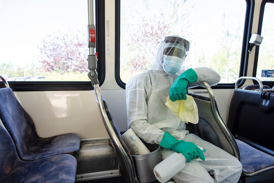 Portrait male worker in clean suit sanitizing public bus