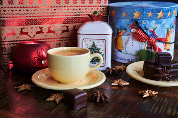 Atmospheric scene of a Christmas decorated wooden table with sweet gingerbread pastry and a coffee cup.