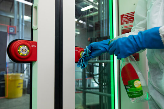 Close up worker in rubber gloves sanitizing subway door