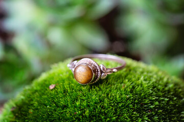 Sterling silver ring with tiger eye gemstone on green moss background
