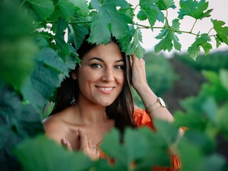 Portrait of a beautiful young woman with natural makeup and healthy skin environment of green leaves. Concept of natural cosmetics and skincare.