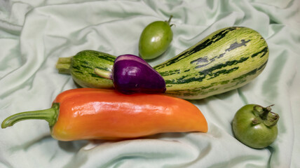 photo of pepper and green tomato. vegetables are on the fabric. vegetarian still life. healthy food. autumn harvest