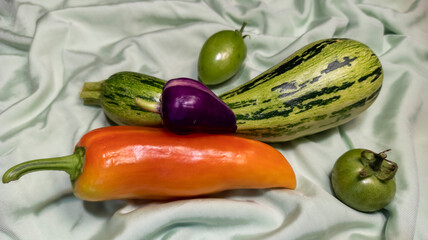 photo of pepper and green tomato. vegetables are on the fabric. vegetarian still life. healthy food. autumn harvest