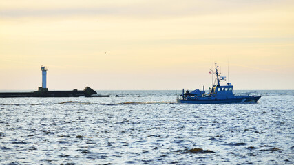 US coast guard ship sailing near the lighthouse at sunset. International (global) security theme © Alex Stemmer