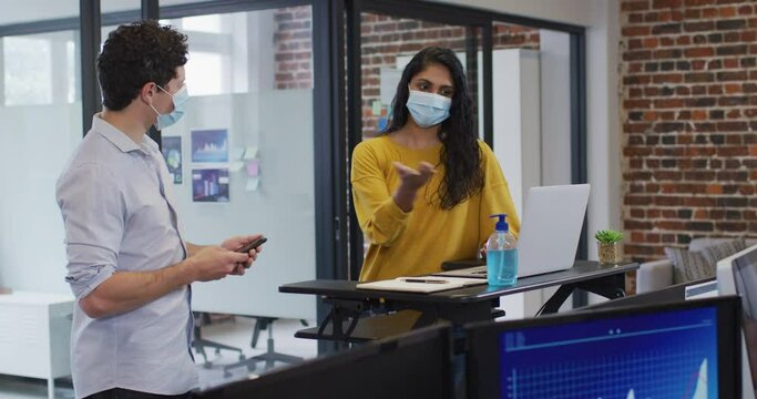 Man and woman wearing face masks working together in office