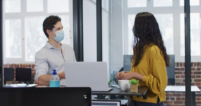1374507Man and woman wearing face masks working together in office