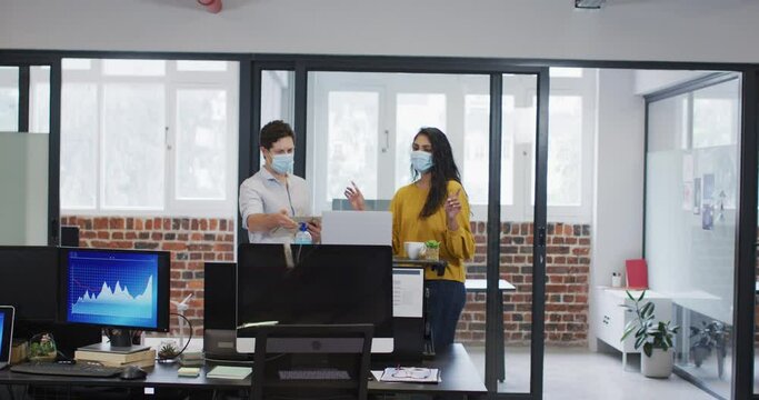 Man and woman wearing face mask working together in office