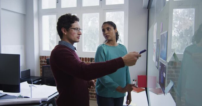 Man and woman discussing over memo notes on white board at office