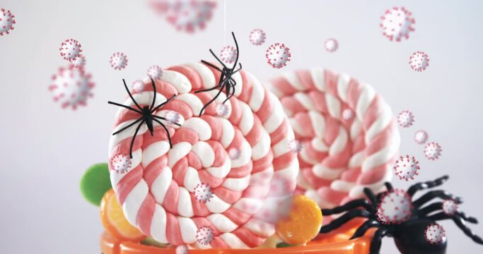 Animation of halloween candy and spiders and orange bucket with multiple covid 19 cells floating on 