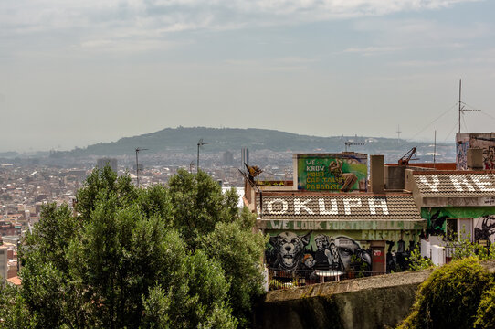 View to the squatted social center roof from Park Guell. Roof sign "Okupa y Resiste" means" "Squat & Resist". Barcelona has most squatter houses in Europe.