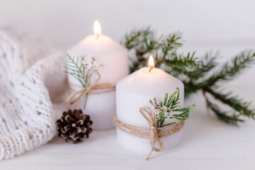 Obraz na płótnie Canvas Christmas candles and fir branches on a white wooden background with lights