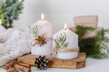 Christmas candles and fir branches on a white wooden background with lights