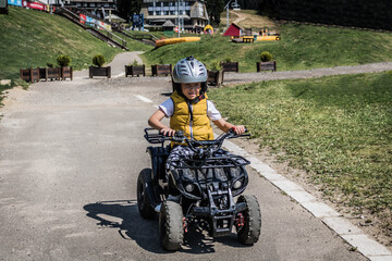Smiling boy learning to drive quadricycle on a track.