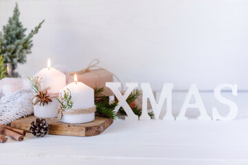 Fototapeta na wymiar Christmas candles and fir branches on a white wooden background with lights
